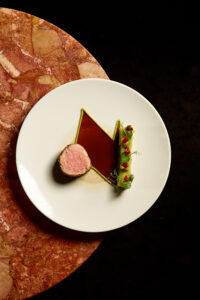 Filet de veau rôti, mousseline de fèves fraîches, tarte fine au poireau, et un jus corsé au vieux porto, relevé de tomates séchées et fèves